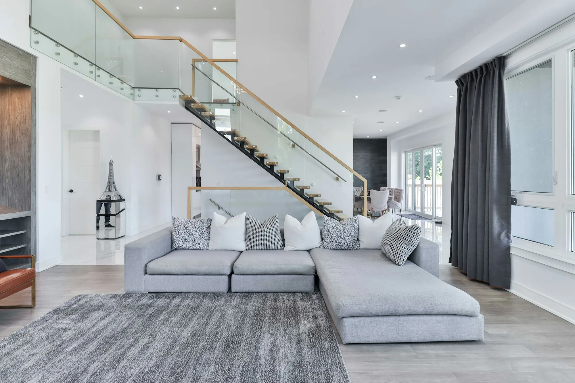 Modern living room with a gray sectional and a floating staircase