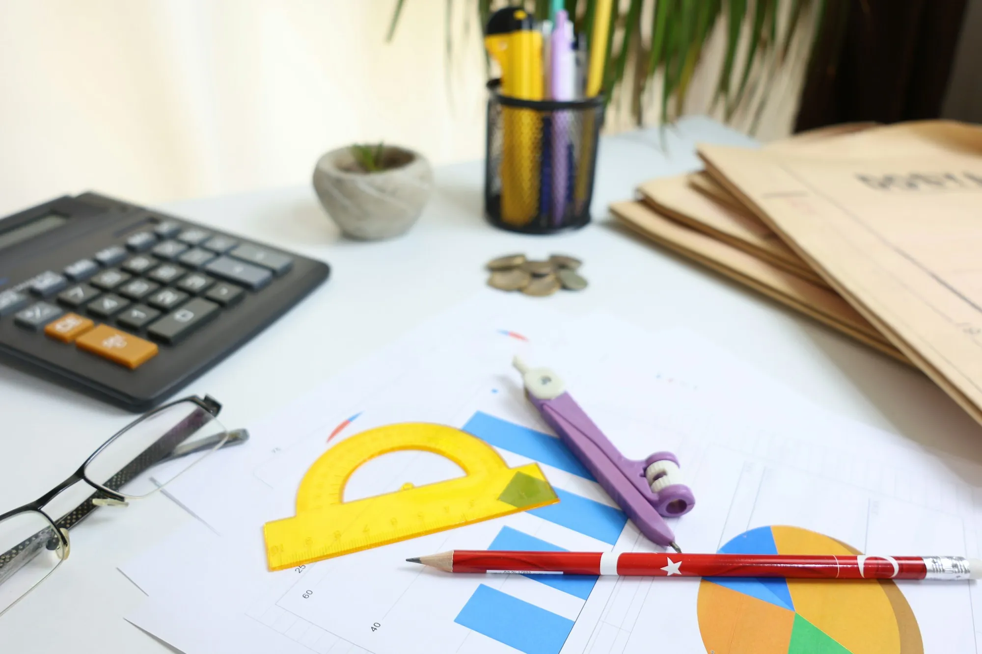 Desk with a calculator, charts, pencils and glasses